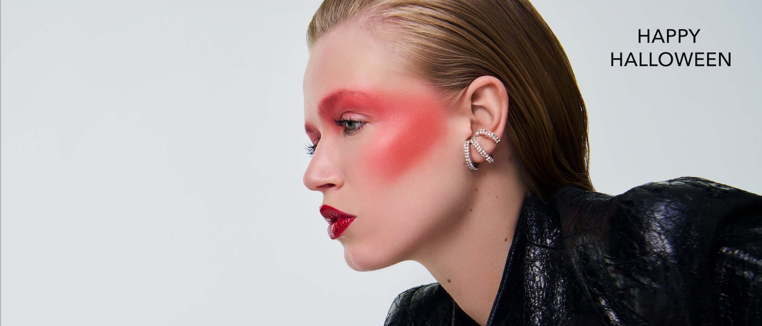 Modelo con maquillaje rojo dramático en ojos y mejillas, labios oscuros y el texto Feliz Halloween, ideal para inspirarte en tu look festivo.