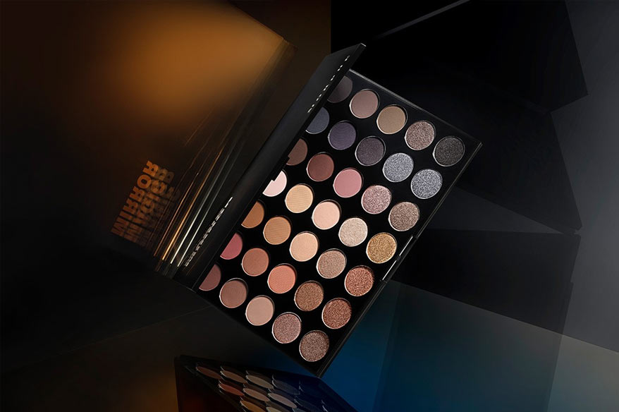 Paleta de sombras de ojos con una variedad de tonos neutros, tierra y brillantes, dispuesta en un estuche negro elegante, perfecta para crear looks versátiles.